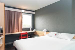 a hotel room with a bed and a desk and a window at ibis Falaise Coeur de Normandie in Falaise