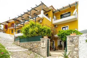a yellow house with plants on a stone wall at Yellow house in Parga