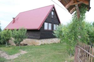 Casa de madera con techo rojo y valla en Vikend kuća Elmina Gorani VISOKO, en Visoko