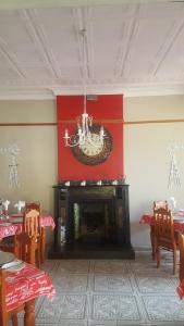 a dining room with a fireplace and a red wall at Oregon Cottage in Ficksburg