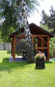 a wooden pavilion with a picnic table and a tree at Agroturystyka Pod Brzozami in Susiec