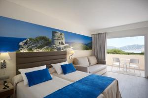 a hotel room with a bed and a view of the ocean at Invisa Hotel Club Cala Blanca in Es Figueral Beach