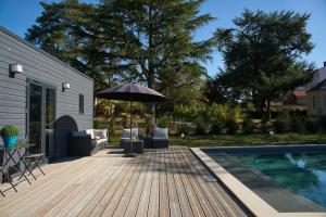 a wooden deck with an umbrella next to a swimming pool at Le Celadon in Montaigu-Vendée