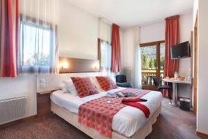 a hotel room with a bed with a red blanket at Vacancéole - Résidence Grand Massif in Morillon