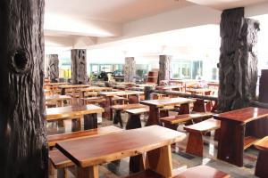 a row of wooden benches in a room with trees at B&B hostel @ Jomtien in Jomtien Beach