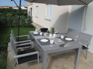 a gray table with two chairs and an umbrella at Apartments Mia Krk in Krk