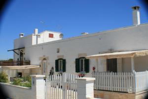 Casa blanca con persianas verdes y valla blanca en Casolare Capitolo, en Cisternino