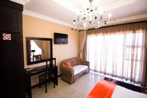 1 dormitorio con lámpara de araña, silla y espejo en The Shamrock Hotel, en Polokwane