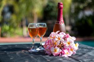 dois copos de vinho ao lado de uma garrafa e flores em The Shamrock Hotel em Polokwane