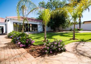 a house with palm trees and flowers in the yard at The Shamrock Hotel in Polokwane