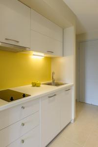 a kitchen with white cabinets and a sink at Yellow house in Parga +6 photos