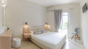 a white bedroom with a bed and a window at Yellow house in Parga