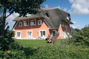 una pareja sentada frente a una casa con techo de paja en Landhaus Morgensünn en Ahrenshoop