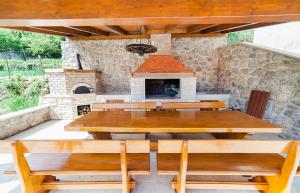 una mesa de madera y bancos frente a un horno de piedra en Apartmani Sandra Rovini, en Mošćenica