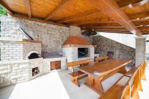 una cocina al aire libre con mesa de madera y un horno de ladrillo en Apartmani Sandra Rovini, en Mošćenica