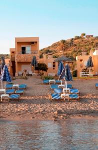 a group of lounge chairs and umbrellas on a beach at Ermis Suites in Platanias