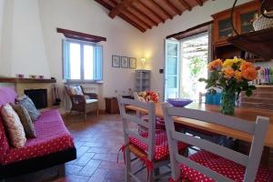 ein Wohnzimmer mit einem Tisch, Stühlen und einer Vase aus Blumen in der Unterkunft Podere Sant'Angelo in Roccalbegna