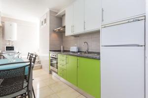 uma cozinha com armários verdes e um frigorífico branco em Apartamento Arenga em Lagos
