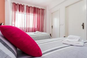 um quarto com 2 camas e uma almofada cor-de-rosa numa cama em Apartamento Arenga em Lagos