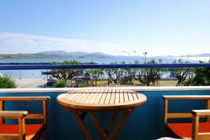a table on a balcony with a view of the ocean at Galazio Limani - Rooms to let in Moúdhros