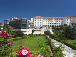 un grand bâtiment blanc avec un jardin et des fleurs dans l'établissement Consolata Hotel, à Fátima