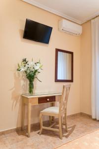 Habitación con escritorio y jarrón de flores en la pared. en Hostal Bianco, en Madrid