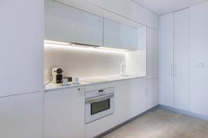 a white kitchen with white cabinets and a stove at Suitopía - Sol y Mar Suites Hotel in Calpe