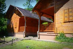 a large wooden building with a porch on it at Favilla Apartmanok2 in Bogács