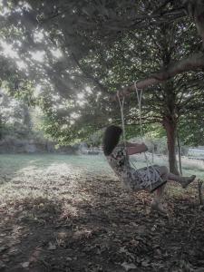 een vrouw zittend op een schommel onder een boom bij ilab rural bed&breakfast in Navia