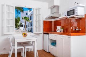 a kitchen with white cabinets and a table and chairs at Carema Garden Village in Fornells
