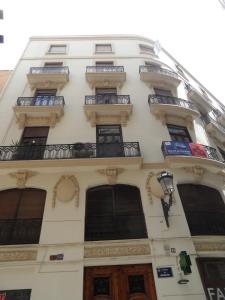 Edificio alto de color blanco con ventanas y balcones en Pensión Moratin, en Valencia