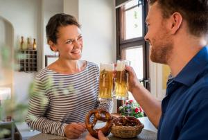 um homem e uma mulher a beber cerveja e um pretzel em Pirnscher Hof - Hotel Garni em Pirna