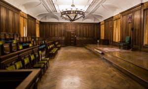 an empty courtroom with green chairs and a chandelier at Hospedería Santa Cruz in San Lorenzo de El Escorial