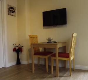 a dining room table with two chairs and a television on the wall at Village Way Apartments in Kincasslagh