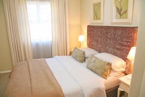 a bedroom with a white bed with pillows and a window at The Winelands Guest House in Bellville