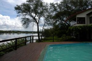 una piscina en una terraza de madera junto a una casa en Kayube Zambezi River House en Livingstone