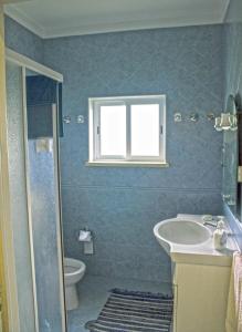 een badkamer met een wastafel, een toilet en een raam bij Casal Do Góis Guest House in Atouguia da Baleia