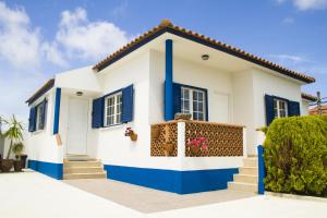 uma casa branca e azul com persianas azuis em Casal Do Góis Guest House em Atouguia da Baleia