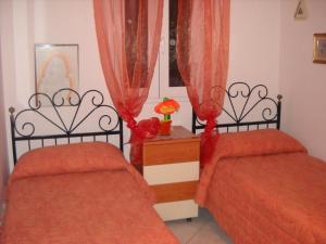 2 letti in una camera con lenzuola e tende rosse di Villa Anna a San Foca