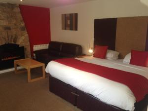 a hotel room with a large bed and a chair at Aberdour Hotel, Stables Rooms & Beer Garden in Aberdour
