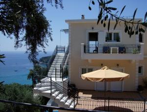 a house with an umbrella and a view of the ocean at Studios Nikolaou Bros in Parga