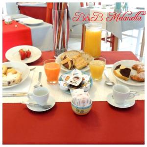 un tavolo ricoperto di piatti per la colazione e succo d'arancia di B&B Melanella a Capaccio-Paestum