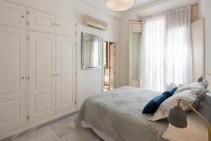 a white bedroom with a bed and a window at INMálaga Catedral 1 in Málaga