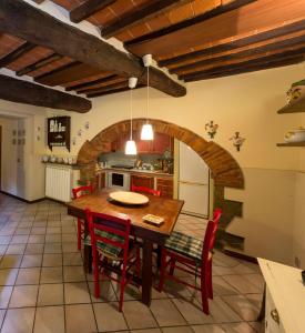een keuken met een houten tafel en rode stoelen bij La Casa del Viaggiatore in Castiglion Fiorentino