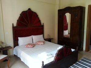 a bedroom with a bed with a red headboard and a mirror at Epavli Veneti in Parga