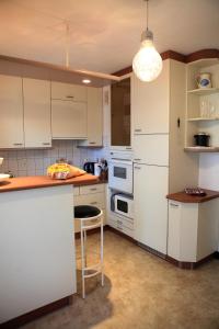 a kitchen with white cabinets and a bar with a stool at Cabane l'hiver in Arcachon