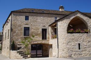 a stone building with flowers in a window at Gite De Charme Caussenard in Le Massegros