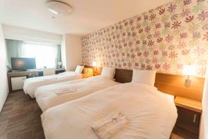 a hotel room with three beds and a tv at Daiwa Roynet Hotel Okinawa-Kenchomae in Naha
