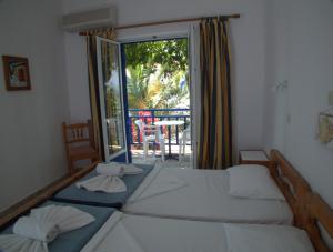 two beds in a room with a view of a patio at Hotel Sofia in Marathokampos