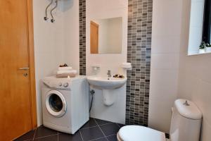 a bathroom with a washing machine and a sink at Sunset Haven Manikata - Walking distance to Golden Bay in Manikata